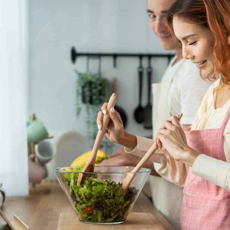Mann und Frau machen in der Küche einen grünen Salat