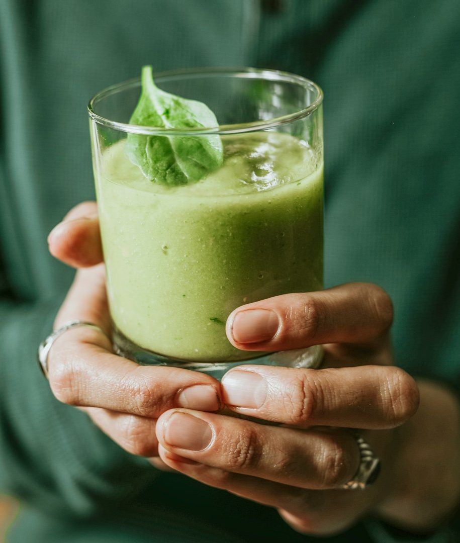 Frau hält einen leckeren, grünen, gesunden Smoothie in den Händen