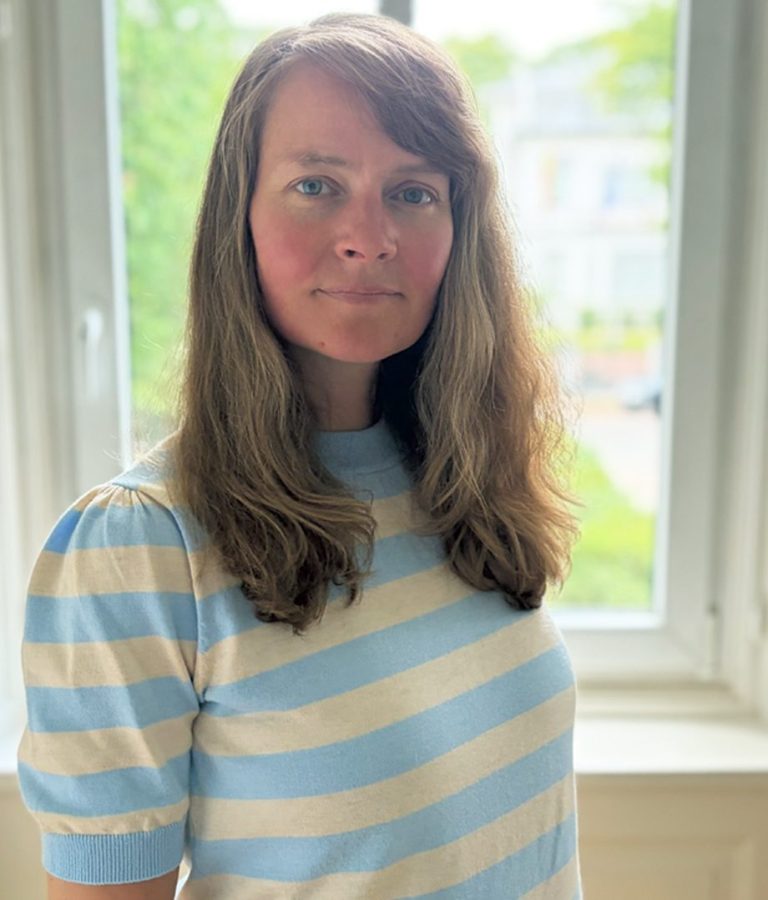 Frau am Fenster und schaut in die Kamera 