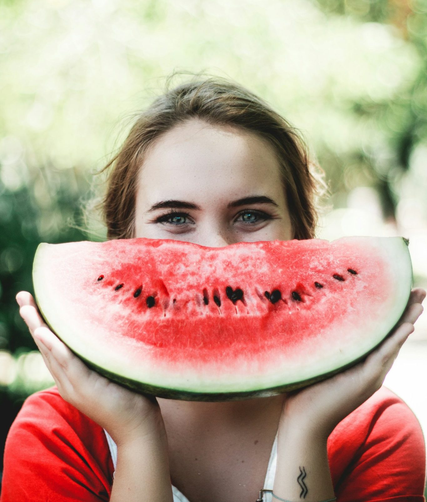 Frau mit Wassermelone vor dem Gesicht, wie ein Mund der lacht